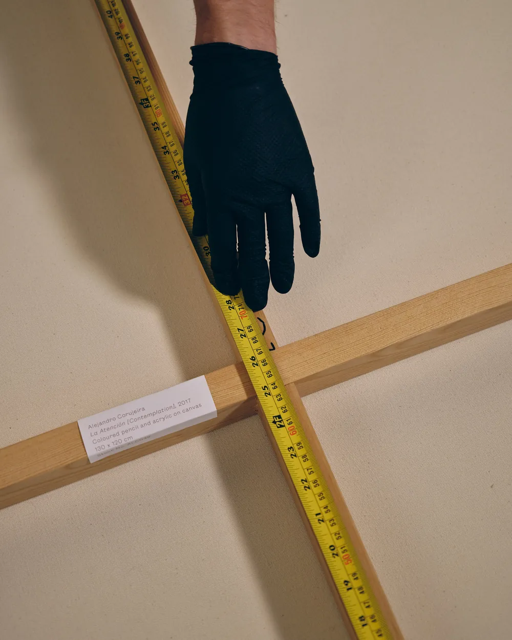 A tape measure laid across the stretcher bars on the back of a canvas.